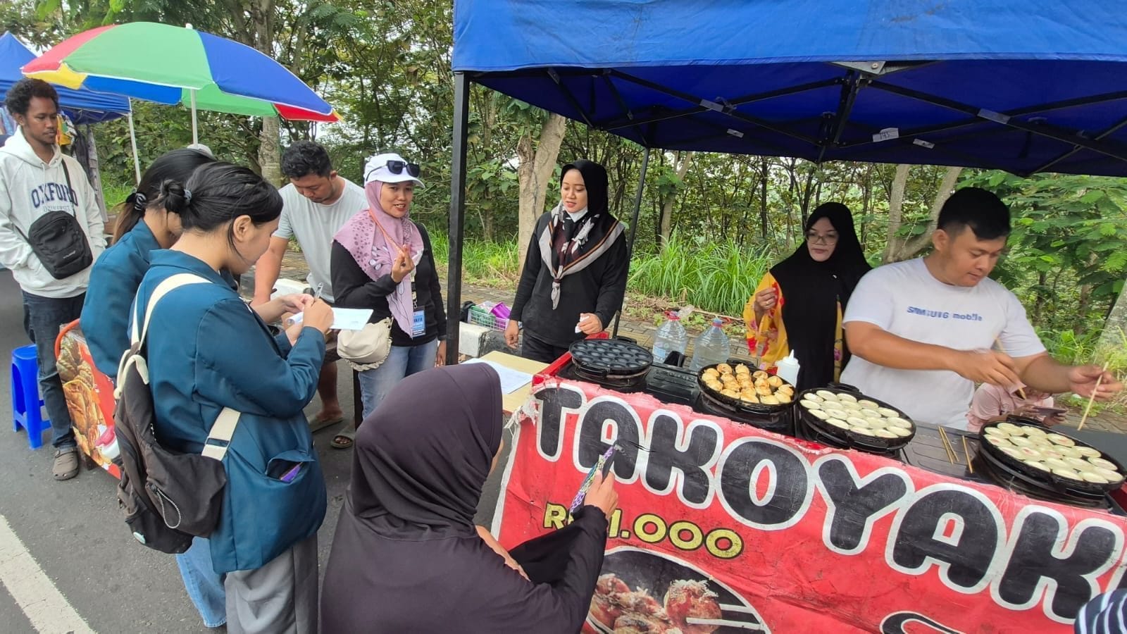 Mahasiswa KKN IDBU 22 ikut membeli makanan yang dijual oleh UMKM pada kegiatan Car Free Day, Minggu (06/07/2025)