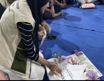 A person sitting on the floor with a sign on the ground Description automatically generated